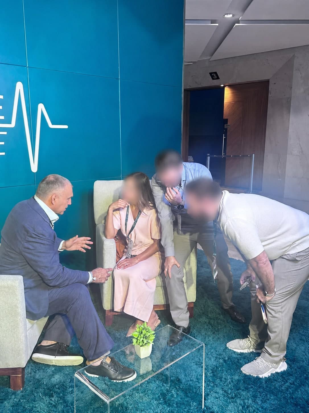Alexander Grinberg, MD, in conversation at a medical conference, with other attendees' faces blurred for privacy